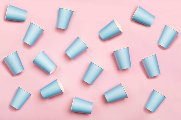 Pattern from mint blue paper drinking cups arranged randomly on pink background. Birthday party celebration abstract fashion baby shower concept. - 写真・画像
