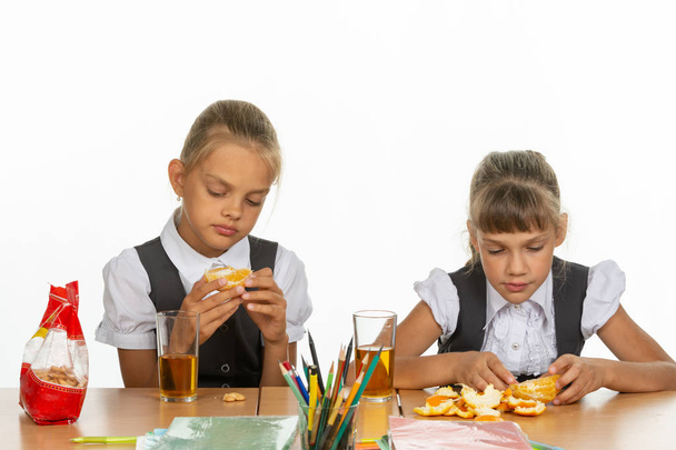 Deux écolières fatiguées en récréation mangent une orange et boivent du jus
 - Photo, image