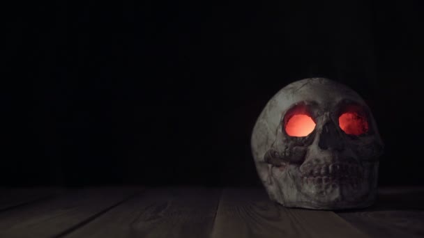 El hombre pone en la mesa de madera el viejo cráneo humano con ojos luminosos y saliendo de ellos en humo
 - Metraje, vídeo