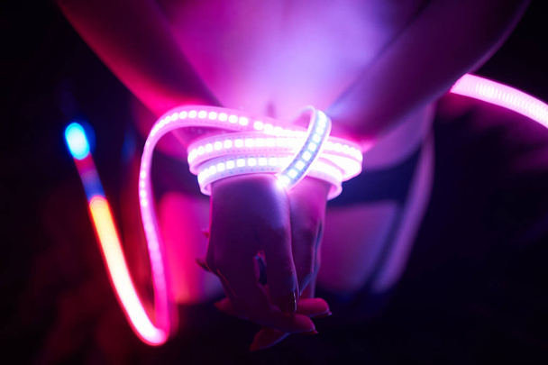 A sexy girl is lit by a neon light. Night club concept. - Φωτογραφία, εικόνα