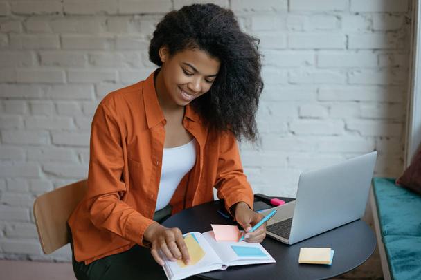Attractive businesswoman working start up project, taking notes, using scrum for productivity. Portrait of happy woman freelancer sitting at workplace. Successful business and career concept    - Photo, Image