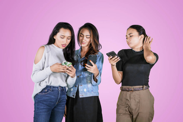 Skupina dospívajících žen pomocí telefonu ve studiu - Fotografie, Obrázek