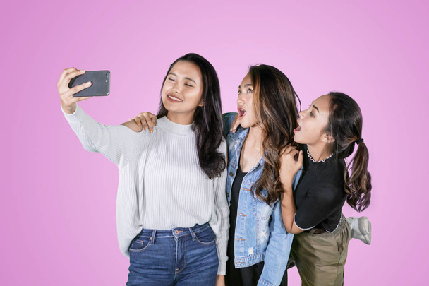 Three female teenagers take a selfie photo on studio - Zdjęcie, obraz