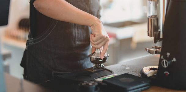 Close-up view of female barista hand's grinding coffee with grinder machine in coffee shop  - Valokuva, kuva