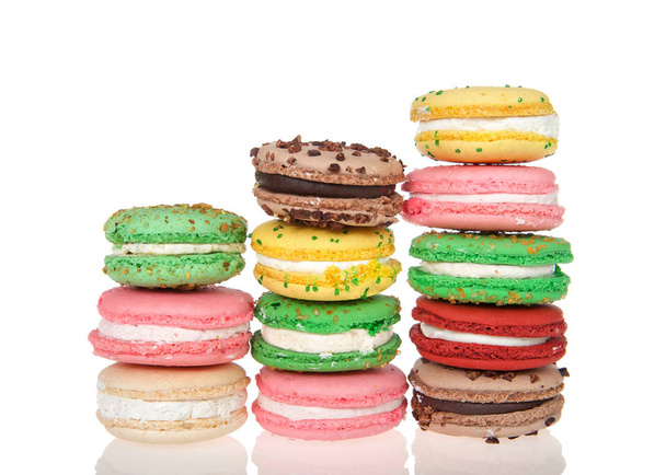 Three stacks varied heights of macaron cookies, multiple colors and flavors on a reflective surface isolated on white. Traditional french treat. - Φωτογραφία, εικόνα