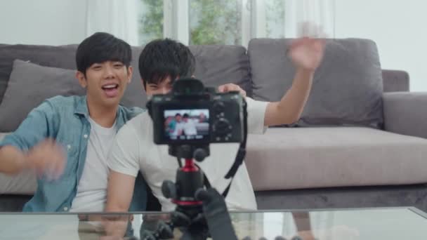 Giovane asiatico gay coppia influencer coppia vlog a casa. Adolescente coreano LGBTQ uomini felice rilassarsi divertimento utilizzando fotocamera registrare video vlog caricare nei social media mentre si trova divano in salotto a concetto di casa
. - Filmati, video