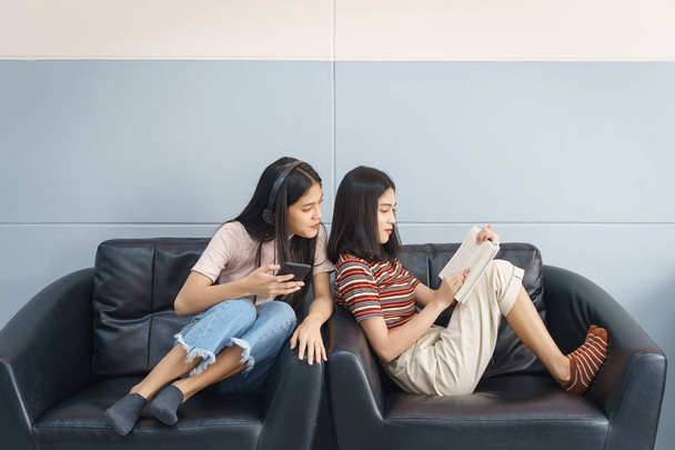 Los adolescentes asiáticos pasan el tiempo libre leyendo el libro y jugando con cel. - Foto, Imagen