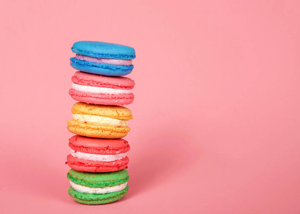 Macaron cookies gestapeld op roze achtergrond, kleurrijke traditionele Franse gebak. - Foto, afbeelding