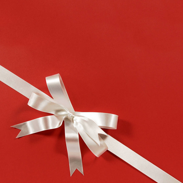 White gift bow ribbon red paper background corner diagonal - Zdjęcie, obraz