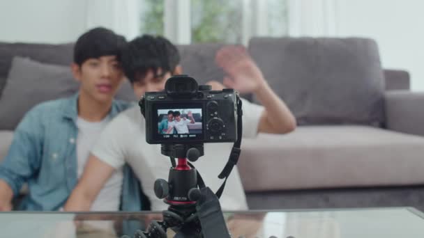 Genç Asyalı eşcinsel çift nüfuzlu çiftler evlerinde video bloğunda. Genç Koreli Lgbtq erkekleri, evdeki oturma odasında kanepede yatarken sosyal medyada video yükleme kamerasıyla rahatlayıp rahatlıyorlar. Yavaş çekim - Video, Çekim