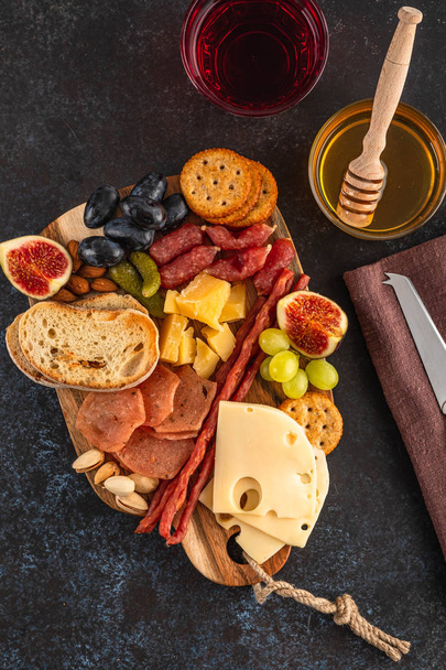 Antipasto catering platter with bacon, jerky, sausage, olive, cheese and grapes on a wooden board. Top view. - Foto, imagen