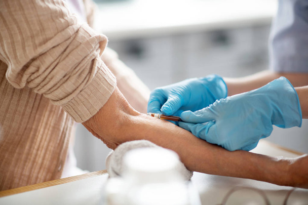 Nurse wearing blue gloves making injection for patient - Φωτογραφία, εικόνα