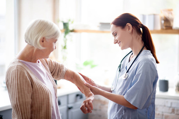 Caregiver putting gel on elbow of retired woman - Foto, Imagem
