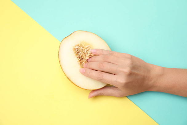 Young woman touching half of melon on color background, top view. Sex concept - 写真・画像