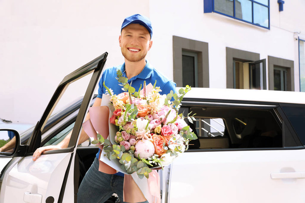 Delivery man with beautiful flower bouquet near car outdoors - Foto, Bild