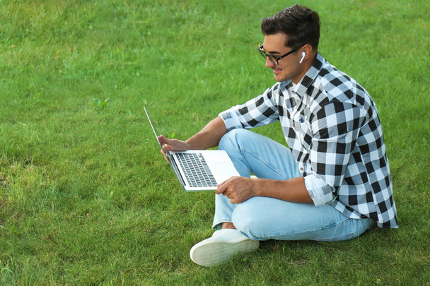 Portrait of young man with laptop outdoors - Fotó, kép