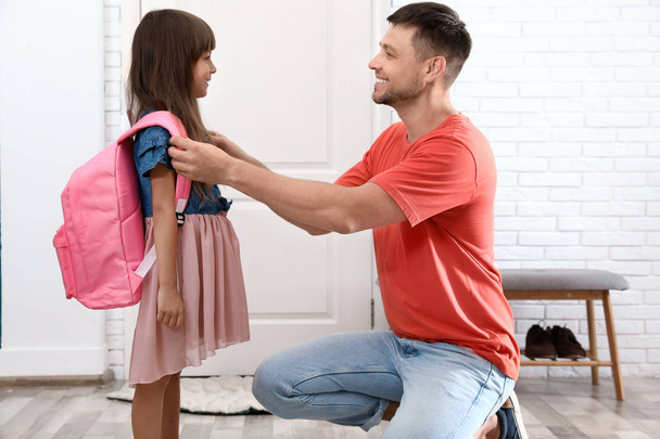 Happy father helping his little child to put on school bag at home - Photo, image