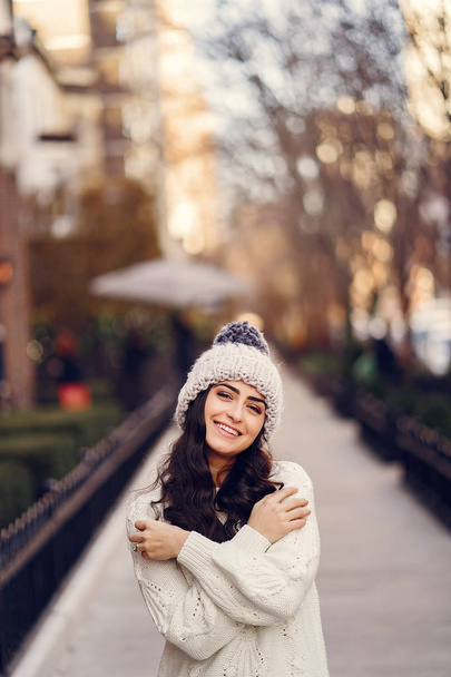 Cute brunette in a white sweater in a city - Zdjęcie, obraz