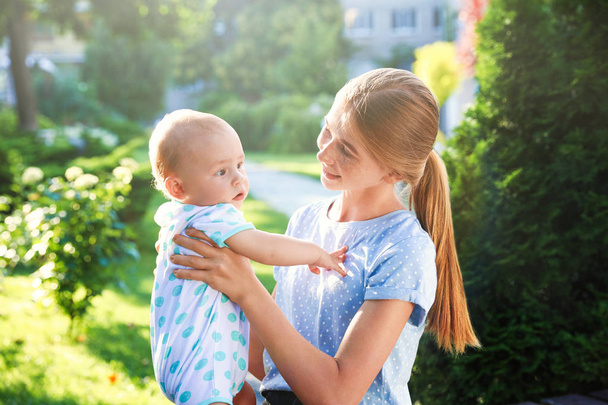 Teen nanny with cute baby outdoors on sunny day - Photo, image