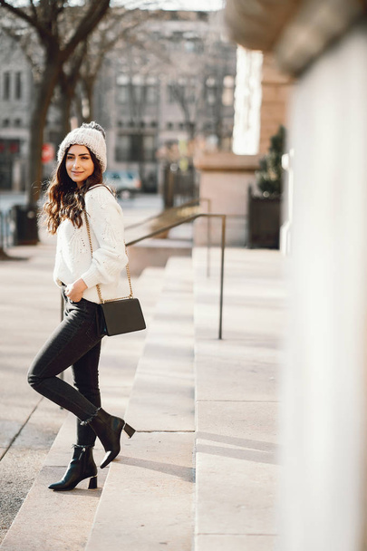 Cute brunette in a white sweater in a city - Valokuva, kuva