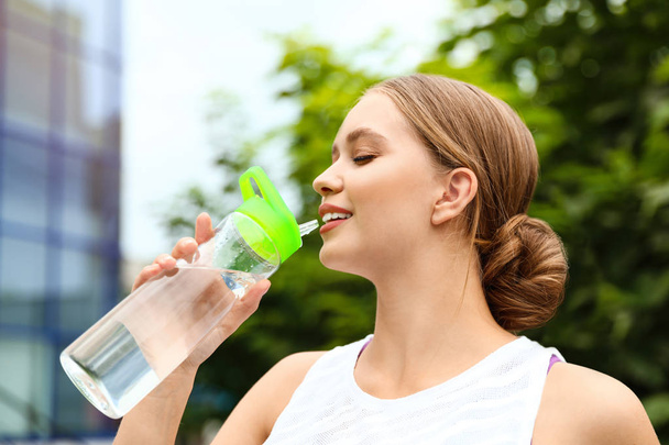 Молодая женщина пьет воду на открытом воздухе. Освежающий напиток
 - Фото, изображение