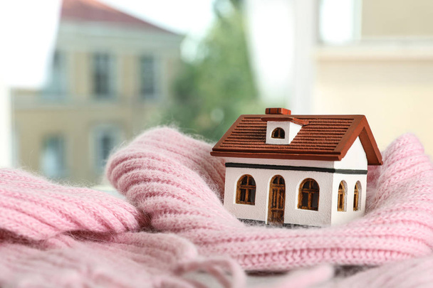 House model and pink scarf on table on blurred background, space for text. Heating efficiency - Photo, Image
