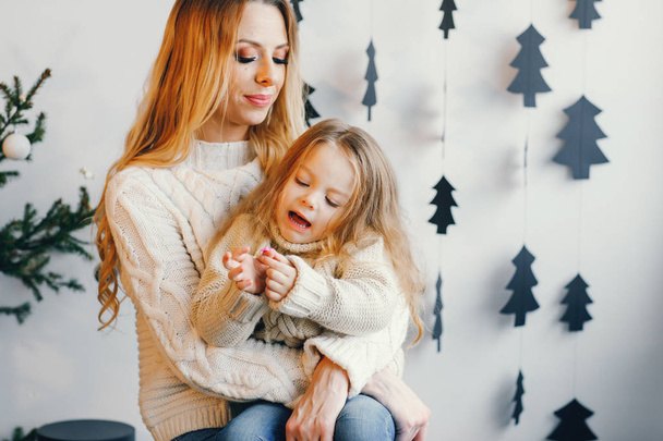 mother and daughter sitting by holiday decorations - Foto, imagen