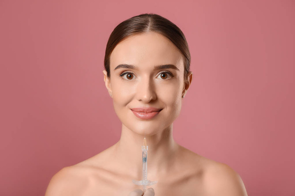 Beautiful woman getting facial injection on pink background. Cosmetic surgery - Fotografie, Obrázek