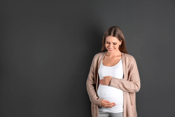 灰色の背景に若い妊娠中の女性。テキスト用のスペース - 写真・画像