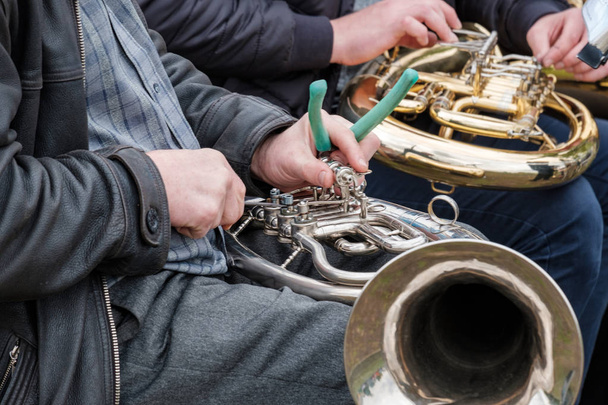 un músico callejero repara un instrumento musical roto en el acto
 - Foto, Imagen