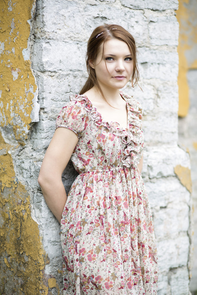 Woman in flowered dress rests on wall - Photo, image