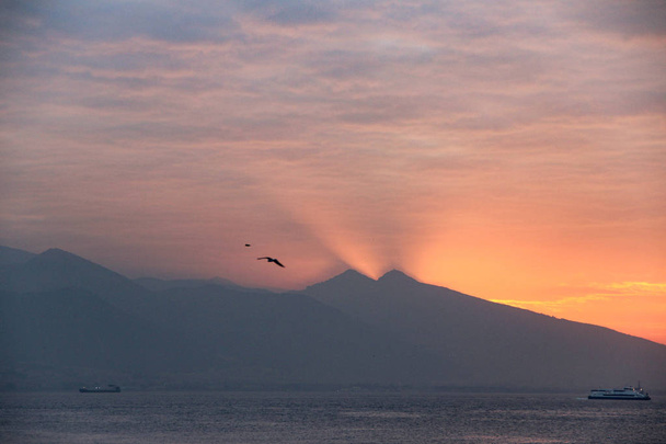Impresionante puesta de sol detrás de la montaña con gaviotas volando sobre el cielo en Turquía
 - Foto, imagen