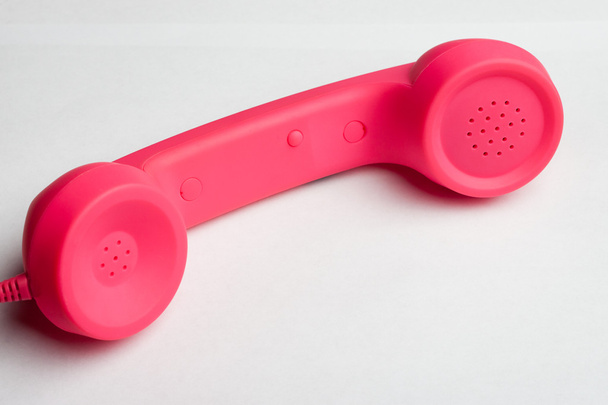 Pink phone on white surface - Foto, afbeelding
