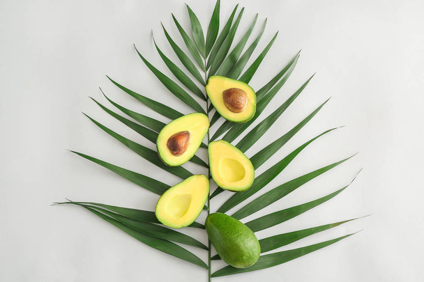 frische reife Avocados und Palmblatt auf weißem Hintergrund - Foto, Bild