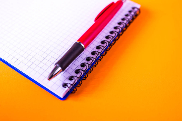 pen en notebook op een oranje achtergrond - Foto, afbeelding