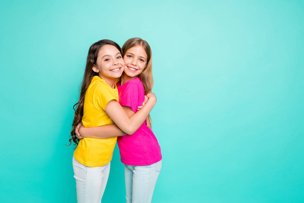 Photo of two cute friendly girlfriends having decided to hug each other while isolated with teal background - Foto, Imagem