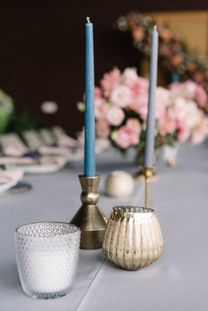 細い長いろうそくと小さな燭台。スタイリッシュな結婚式の花。休日のテーブルの上の青いろうそく - 写真・画像