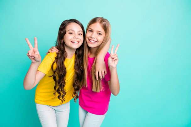 Photo of two excited cheerful nice cute girls showing you v-sign while isolated with teal background - Foto, Bild