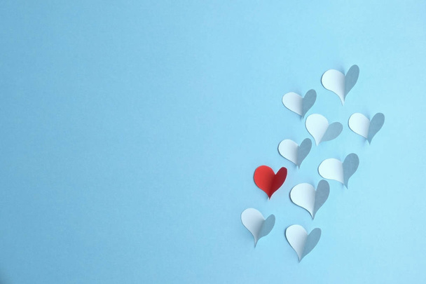 Paper hearts on blue background. Red paper heart with several blue ones.  - Photo, Image