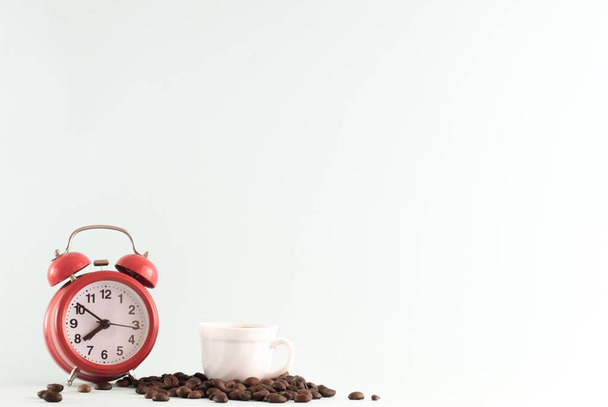 A retro stílusú vörös ébresztőóra és egy csésze forró kávét kávébab. Reggeli kávékészítési koncepció. - Fotó, kép