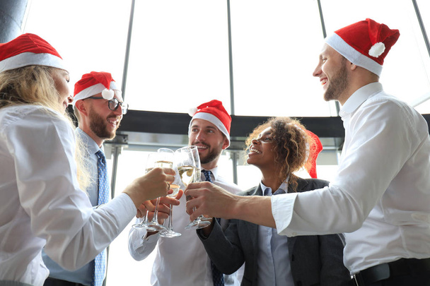 Współpracownicy biurowi świętują zimowe wakacje razem w pracy i piją szampana w biurze. Wesołych Świąt i Szczęśliwego Nowego Roku. - Zdjęcie, obraz