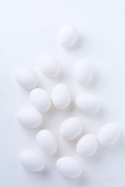 Λευκά ωμά αυγά κοτόπουλου ξαπλωμένα σε ελαφρύ τσιμεντένιο φόντο. Άνω όψη. - Φωτογραφία, εικόνα