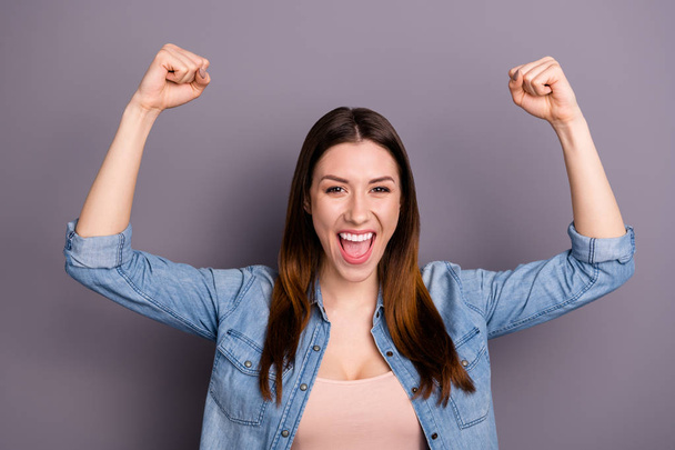 Portrait of crazy delighted woman raise her fists shout yeah celebrate victory wear denim jeans outfit isolated over grey color background - Fotó, kép