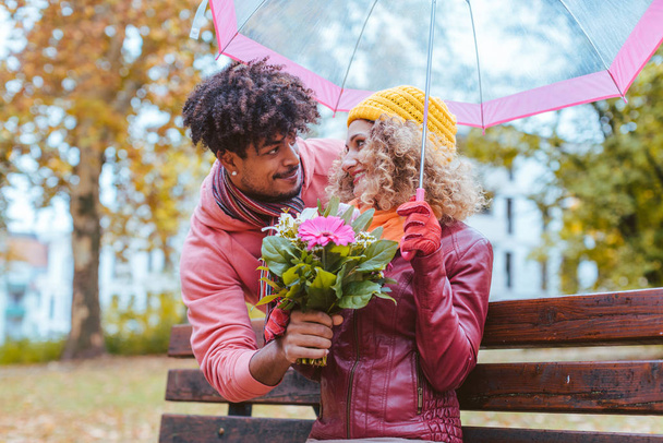 Mann überrascht seine Frau an einem trüben Herbsttag mit einem Blumenstrauß - Foto, Bild