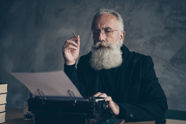 Close-up portrait of his he nice attractive focused concentrated bearded gray-haired professional creative publisher typing keyboard life story article essay diary over concrete wall background - Valokuva, kuva