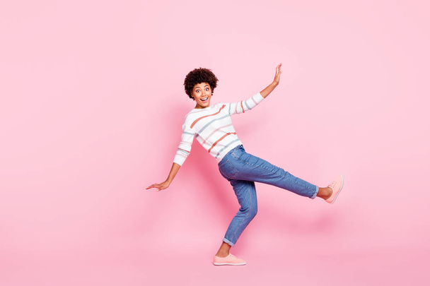Полное фото профиля тела довольно темной женщины на танцах класса обучения новым современным движениям носить полосатый пуловер и джинсы изолированные пастельно-розовый цвет фона
 - Фото, изображение