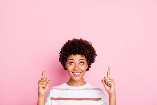 Closeup photo of amazing dark skin wavy lady indicating fingers up empty space interested with shopping prices wear striped pullover isolated pastel pink color background - Foto, Bild