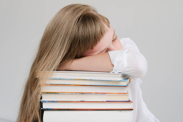 Schattig klein meisje slaapt op een top van een stapel boeken - Foto, afbeelding