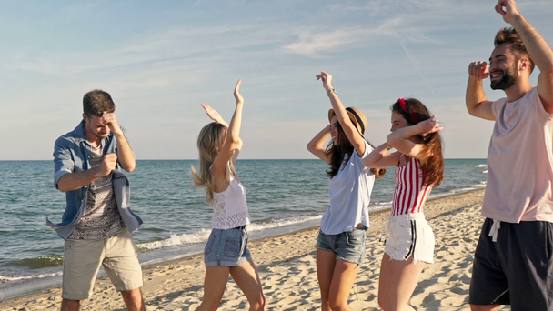 Skupina mladých radujících se přátel tančí při společné zábavě u moře - Záběry, video