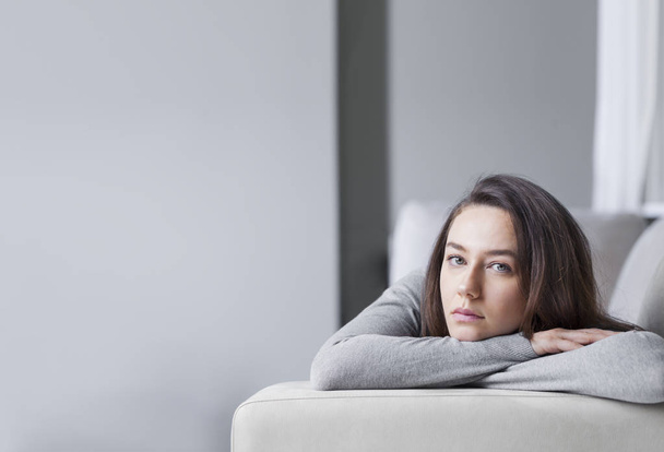Depressed young woman on sofa at hom - Foto, Imagen